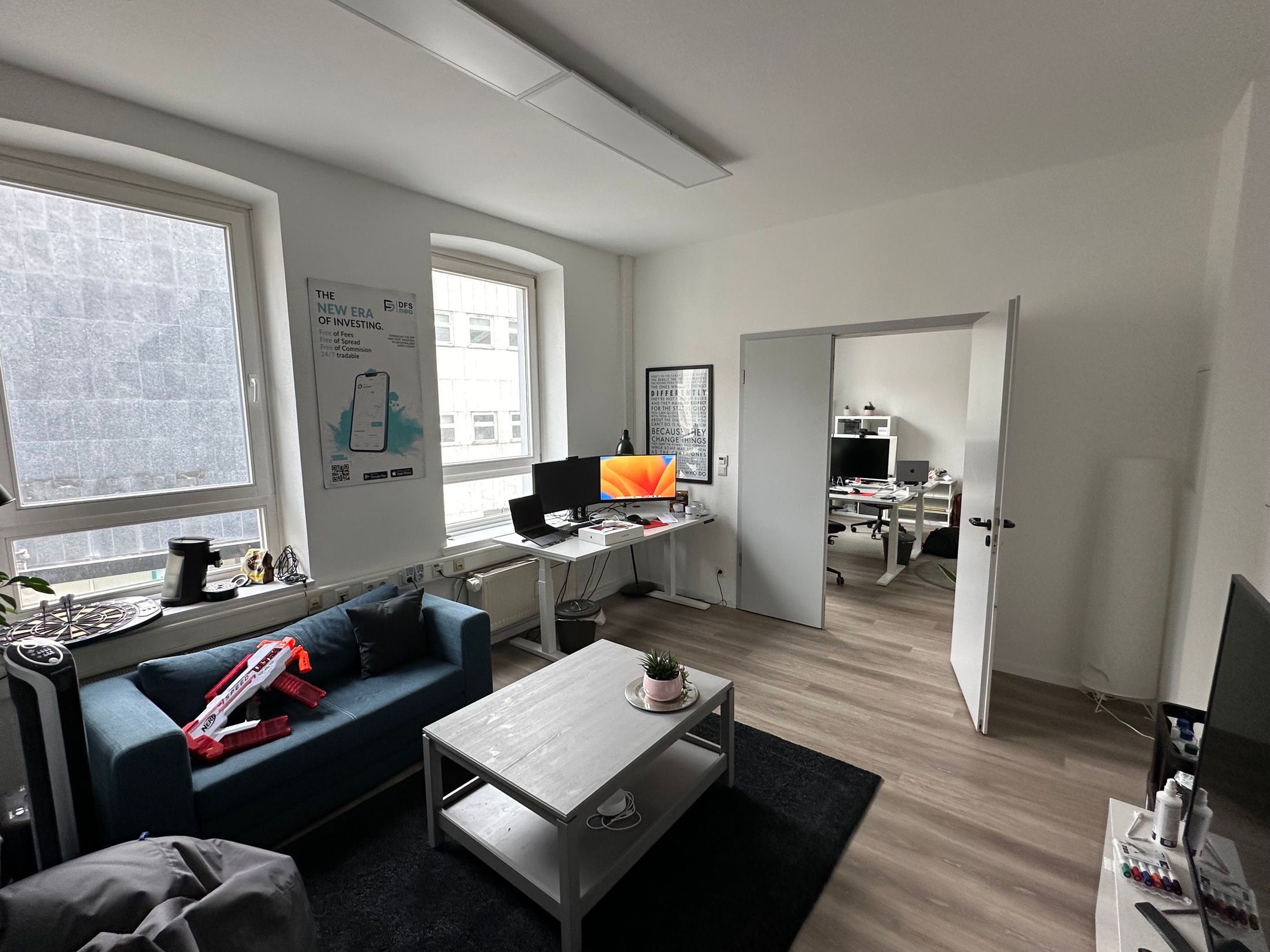 Lounge-Bereich des Büros mit blauem Sofa und Blick in den zweiten Arbeitsraum